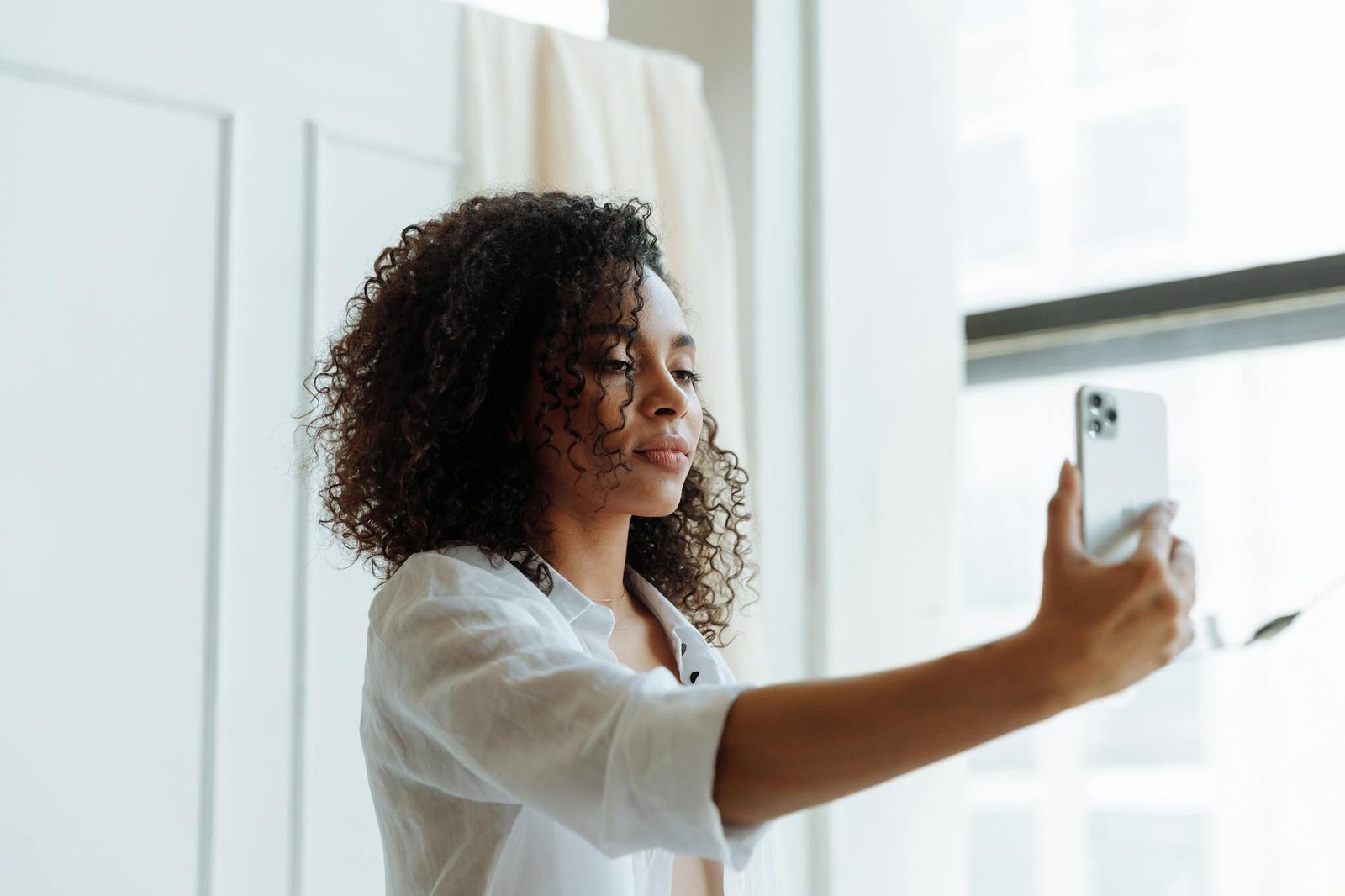 Anneau lumineux surélevé et décalé sur le côté d'un visage, le smartphone posé sur son propre trépied face au sujet.